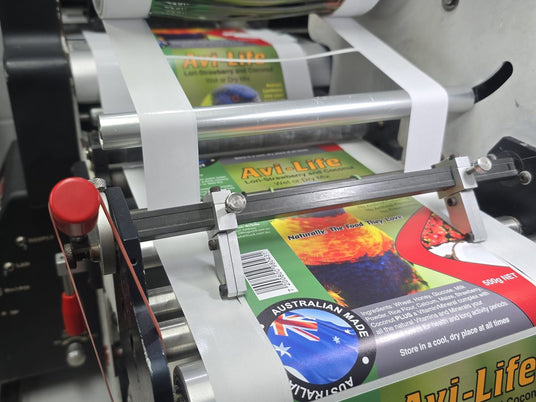 Printed roll labels running through the label finishing machine in the Sticker Studio workshop