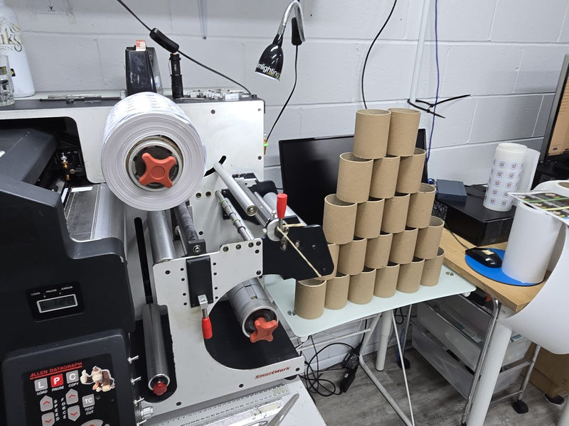Digital label finishing machine beside a stack of cardboard label roll cores