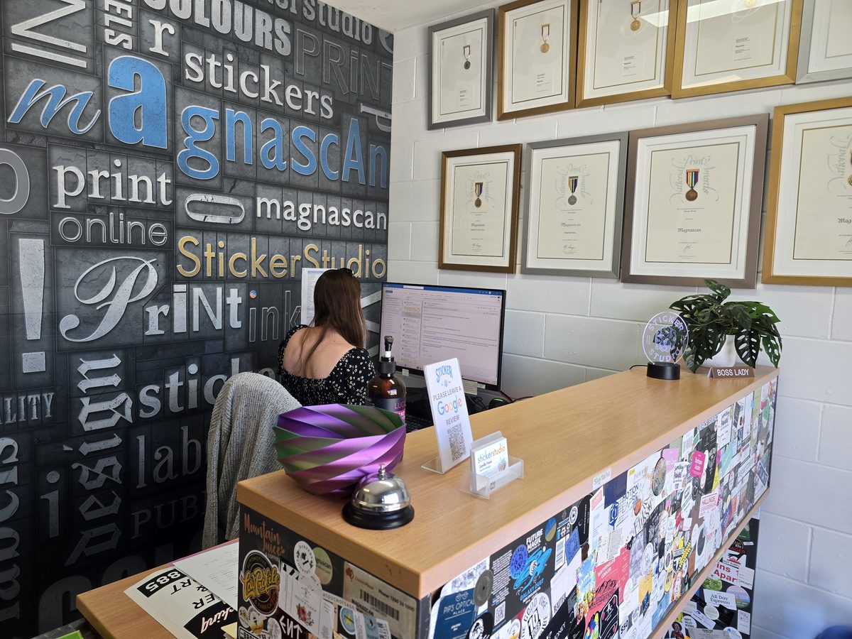 Sticker Studio reception with the Magnascan word wall and framed printing award medals